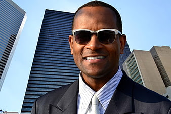 Confident African American businessman in suit and sunglasses in city
