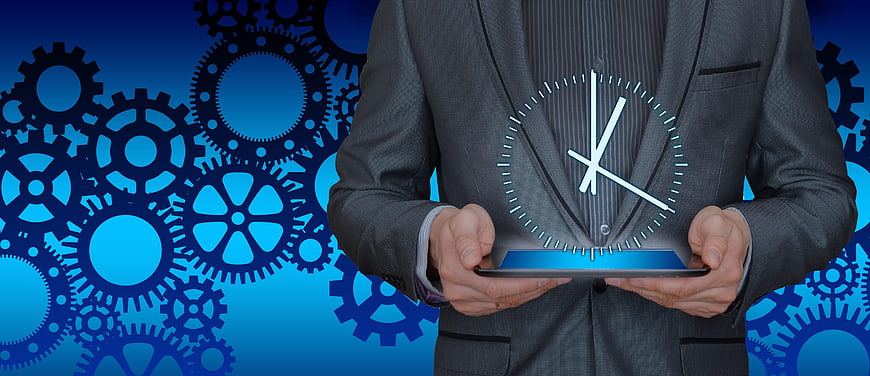 Businessman holding tablet with holographic clock and gears background