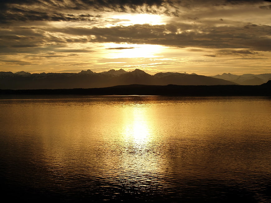 Golden Sunset Over Calm Lake with Mountain Silhouette