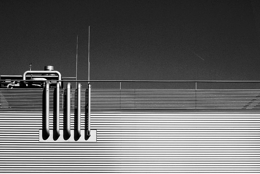 Black and white industrial pipes on corrugated metal wall