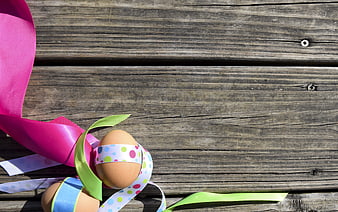 Easter eggs with colorful ribbons on rustic wooden background