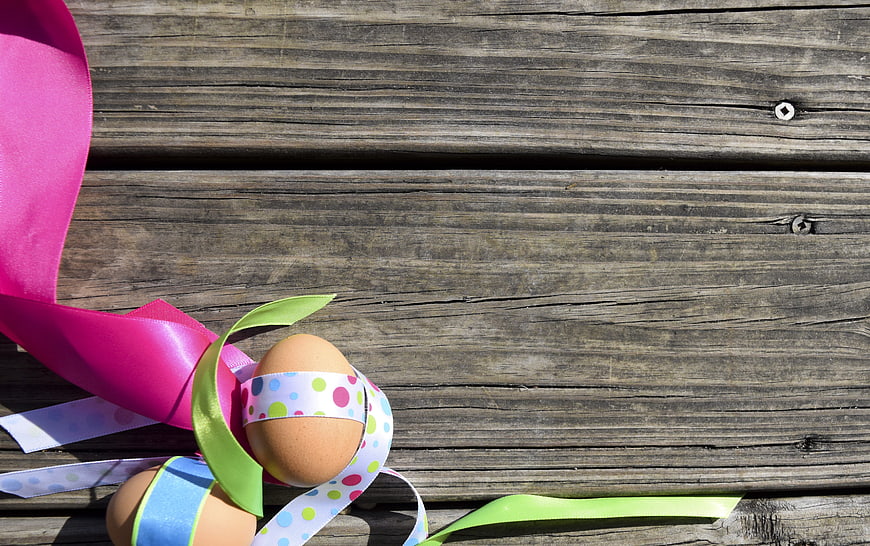 Easter eggs with colorful ribbons on rustic wooden background
