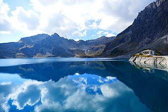 Serene Alpine Lake with Mountain Reflections and Cliffside Building