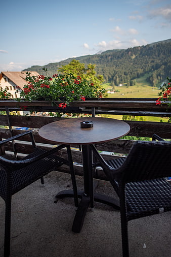 Outdoor balcony table with mountain view and red flowers