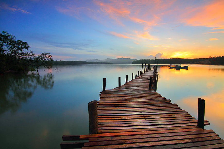 Wooden pier extending into calm lake at sunset