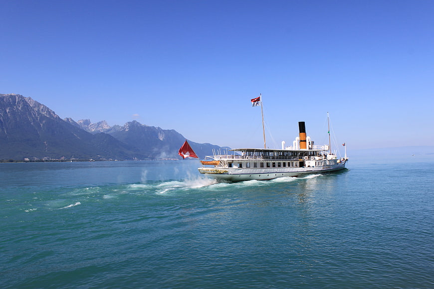 Classic Steamship Cruising On Lake Geneva With Alpine Mountains In Background