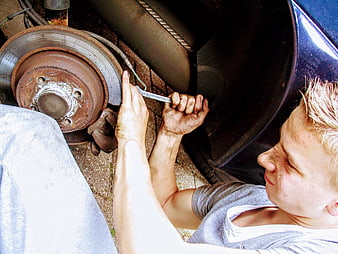 Young Man Repairing Car Brake Disc With Wrench
