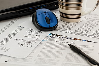 Office desk with tax documents, blue mouse, and coffee cup