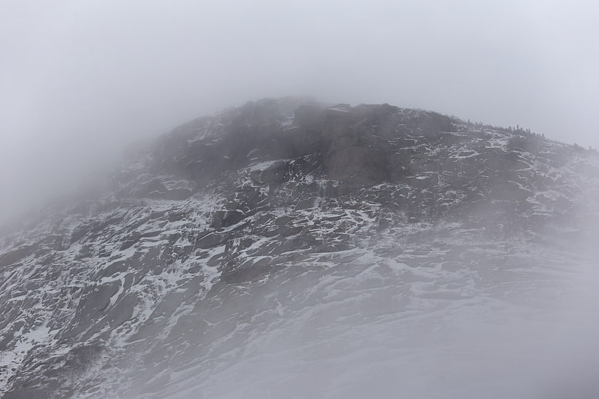 Snowy mountain peak shrouded in thick fog and mist