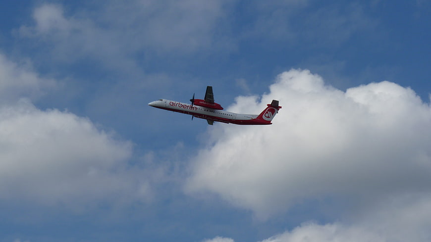 Air Berlin turboprop airplane flying in blue sky with clouds