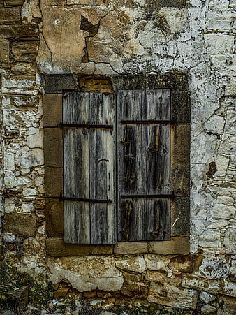 Weathered wooden shutters on old stone wall