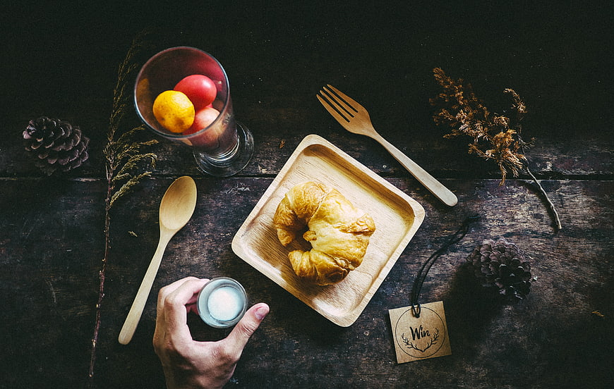 Top view of croissant breakfast with wooden cutlery and fruit