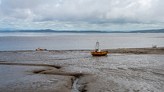 Yellow fishing boat stranded on muddy tidal flats