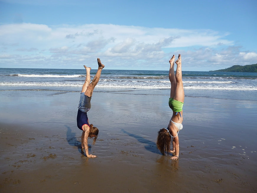 Two Women Performing Handstands on Wet Sandy Beach