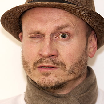 Close-up portrait of a man in a brown hat winking