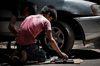 Young boys working as car mechanics on a tire