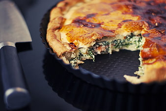 Homemade spinach quiche with golden crust in baking pan
