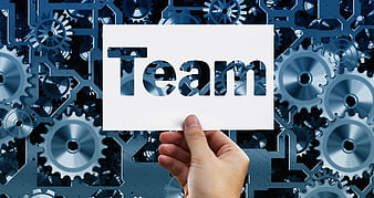 Hand holding white card with Team text against blue mechanical gears background