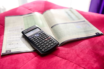 Scientific calculator on open textbook on red fabric