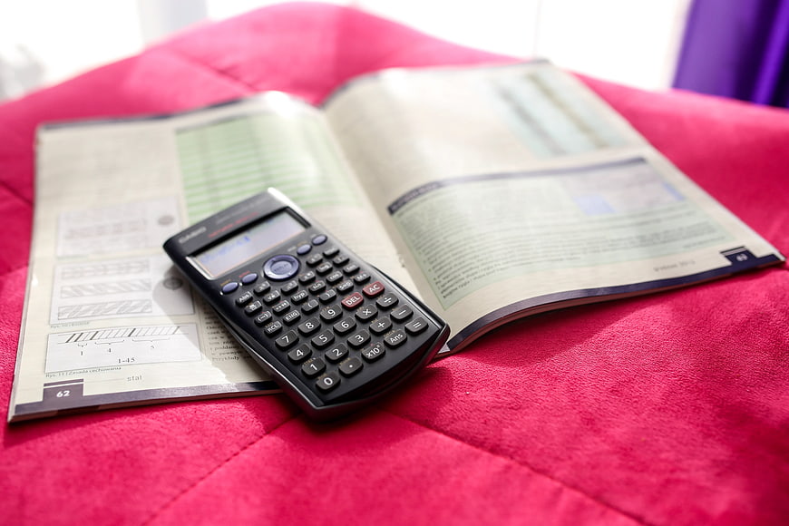 Scientific calculator on open textbook on red fabric