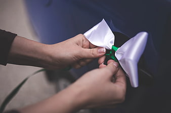 Close-up of hands tying a white satin bow