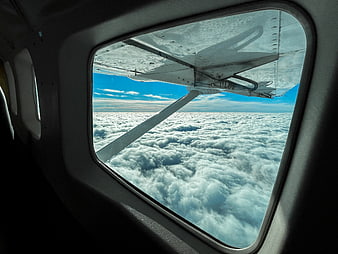 Airplane wing view above clouds from window