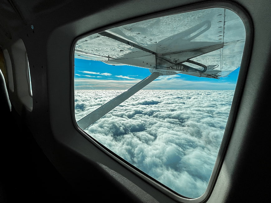 Airplane wing view above clouds from window