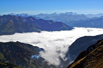 Sea of clouds in mountain valley with autumn foliage