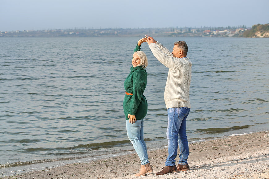 Happy Senior Couple Dancing on Sandy Beach by Sea