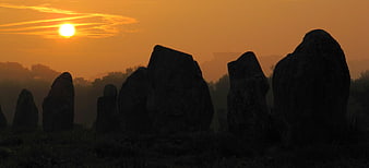 Silhouetted Ancient Stone Monoliths Against Golden Sunrise Sky