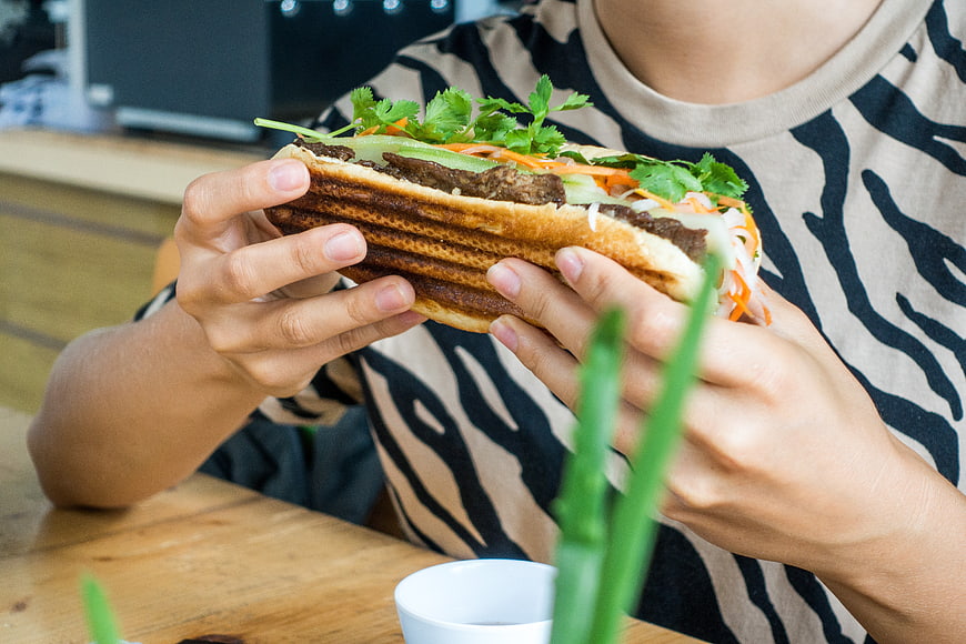 Close-up of hands holding fresh Vietnamese Banh Mi sandwich