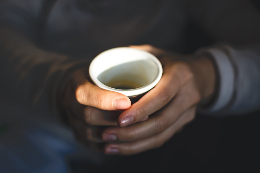 Close-up of hands holding a white coffee cup