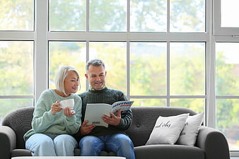 Happy senior couple reading interior design magazine on sofa
