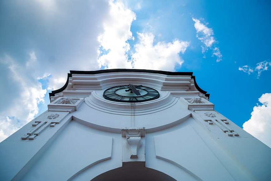 Low angle view of white clock tower against blue sky