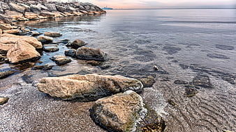 Rocky shoreline with clear water and distant city skyline
