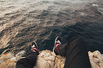 POV sitting on cliff edge overlooking ocean waves