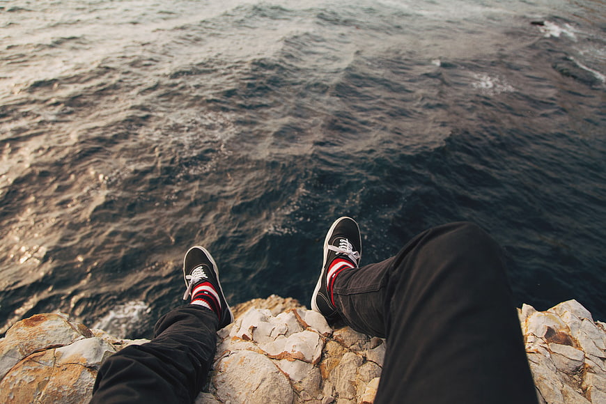 POV sitting on cliff edge overlooking ocean waves
