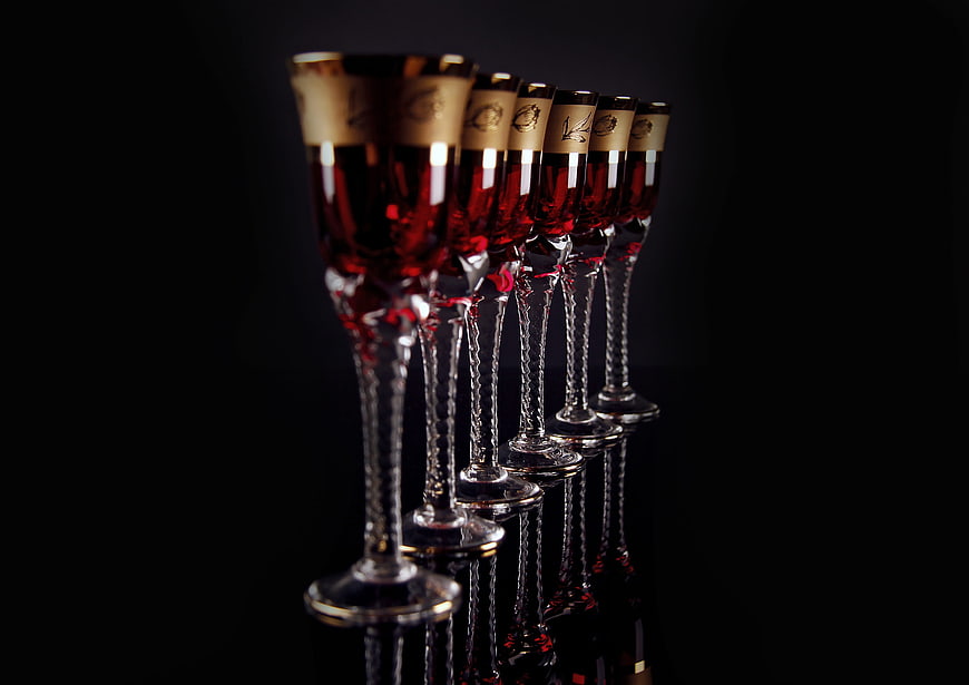 Elegant red wine glasses with gold rims on black background