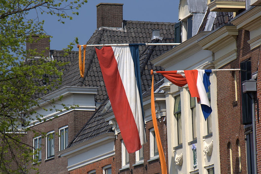 Dutch flags hanging on traditional brick buildings