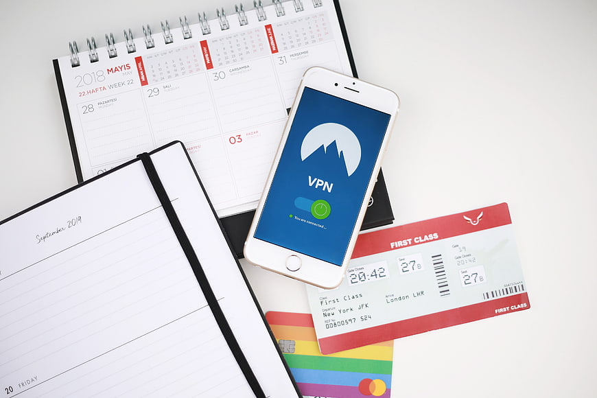 Smartphone with VPN app, flight ticket, and calendar on white desk