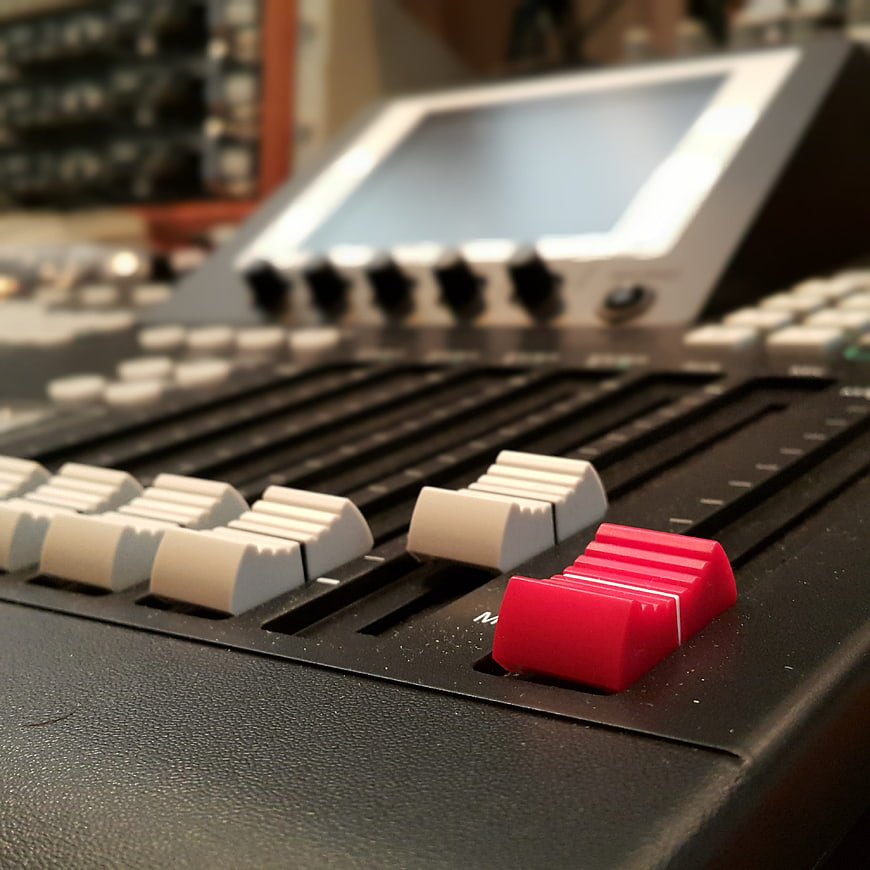Close-up of audio mixing console with red fader