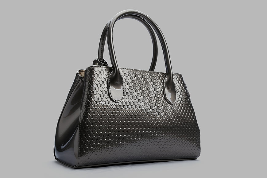 Glossy Black Textured Leather Handbag on Gray Background