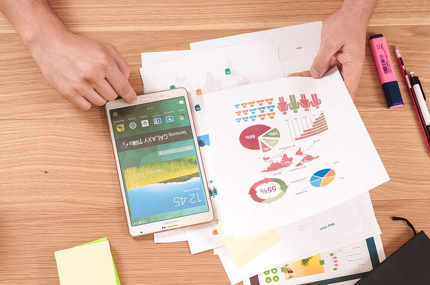 Businessman analyzing charts and infographics on wooden desk
