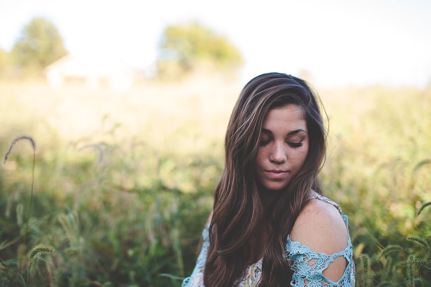 Serene young woman in blue lace dress in field