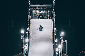 Snowboarder performing aerial trick on night slope at Air + Style event