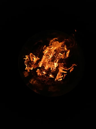 Close-up of burning logs in a dark fire pit at night