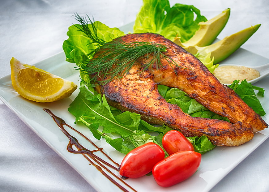 Grilled Salmon Fillet with Salad and Lemon on White Plate