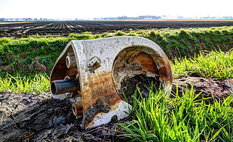 Rusted metal plow part in green field