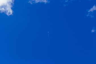 Tiny Airplane with Contrails in Deep Blue Sky