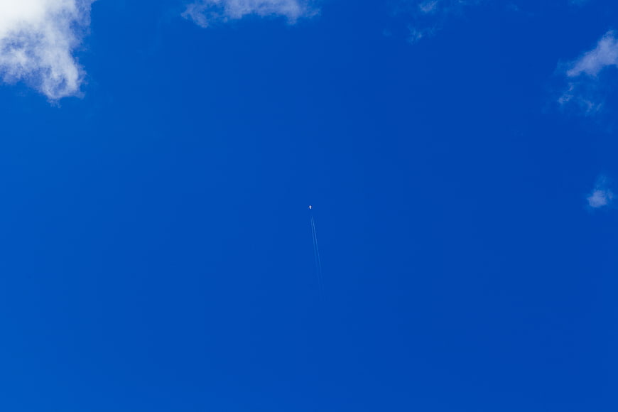 Tiny Airplane with Contrails in Deep Blue Sky